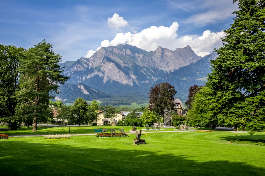 bosque verde con varias casas de madera junto a un lago en Suiza durante la primavera