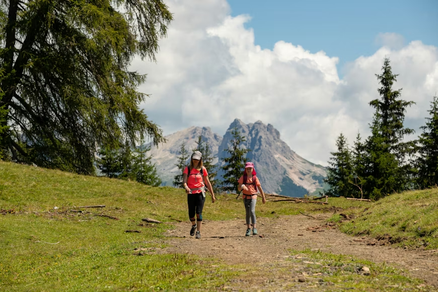 senderistas recorriendo un sendero en los Alpes suizos durante el verano con una montaña de fondo